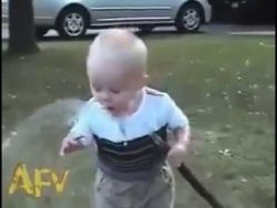 Kind versucht Wasser durch Gartenschlauch zu trinken kind versucht wasser durch garte