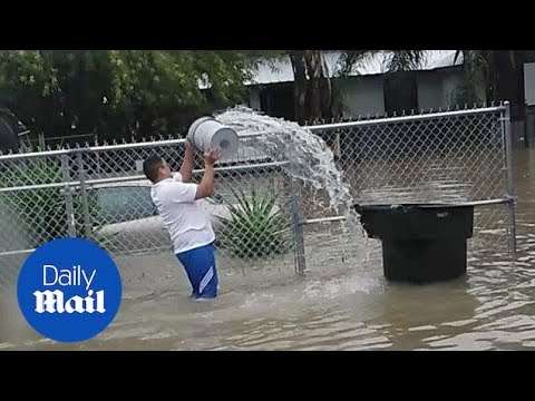 Mann schaufelt Wasser über einen Zaun wasser zaun