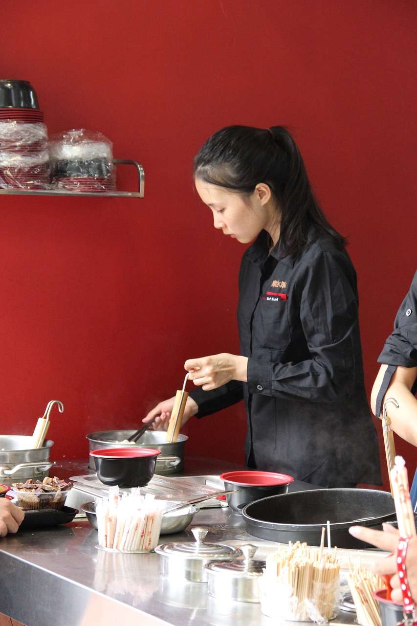 Junge Köchin schwingt den Topf am Herd junger koch